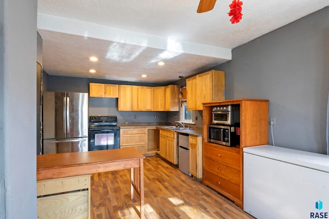 kitchen featuring sink, stainless steel appliances, pendant lighting, a textured ceiling, and light hardwood / wood-style floors