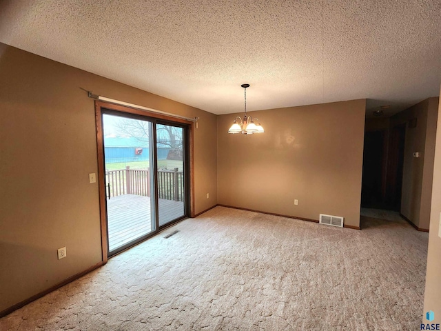 carpeted spare room featuring a textured ceiling and a chandelier