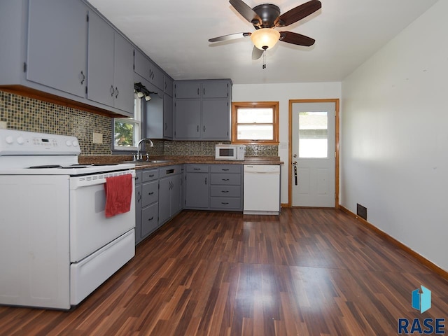 kitchen with a healthy amount of sunlight, sink, white appliances, and dark wood-type flooring