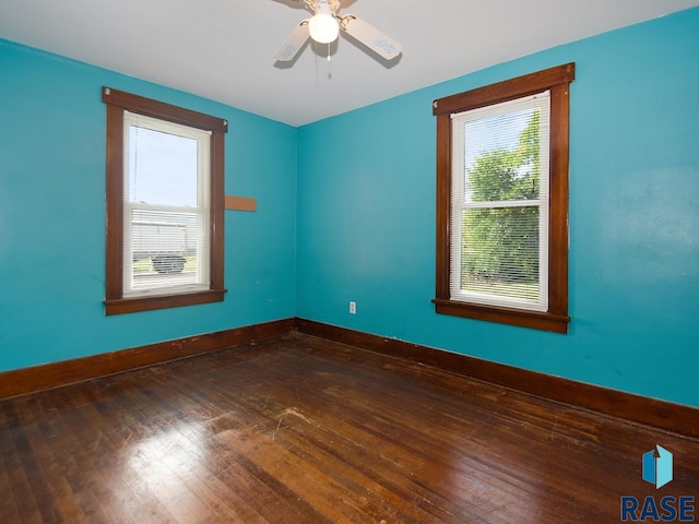 empty room with a wealth of natural light, ceiling fan, and dark wood-type flooring