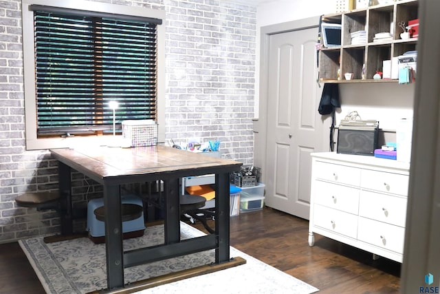 office with dark wood-type flooring and brick wall