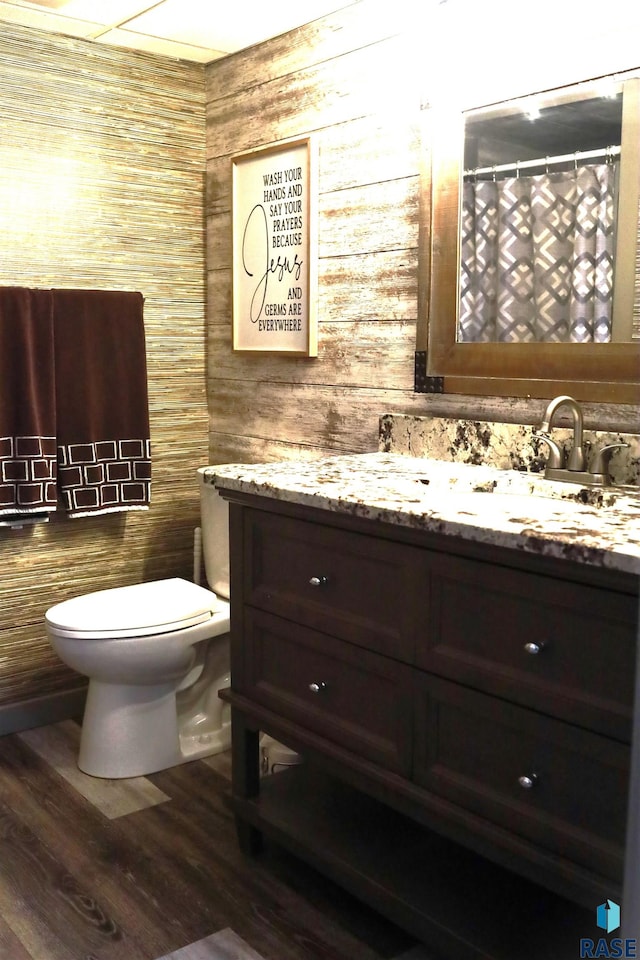 bathroom with vanity, toilet, wood-type flooring, and wooden walls