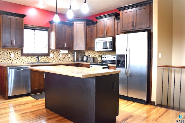 kitchen with pendant lighting, a center island, light hardwood / wood-style floors, and appliances with stainless steel finishes