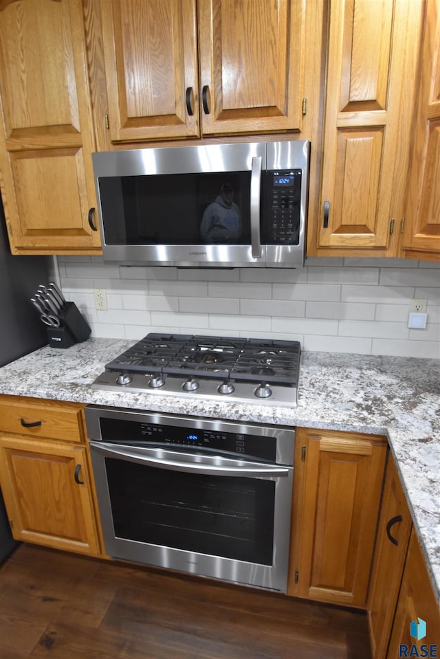 kitchen featuring tasteful backsplash, light stone counters, and stainless steel appliances