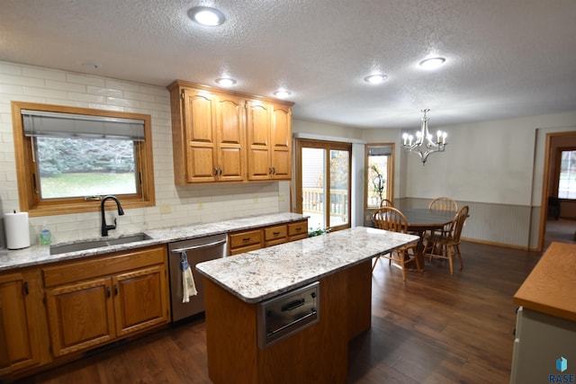 kitchen featuring stainless steel dishwasher, sink, pendant lighting, a notable chandelier, and dark hardwood / wood-style floors