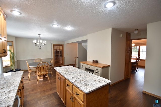 kitchen with a textured ceiling, dark hardwood / wood-style flooring, a center island, and decorative light fixtures