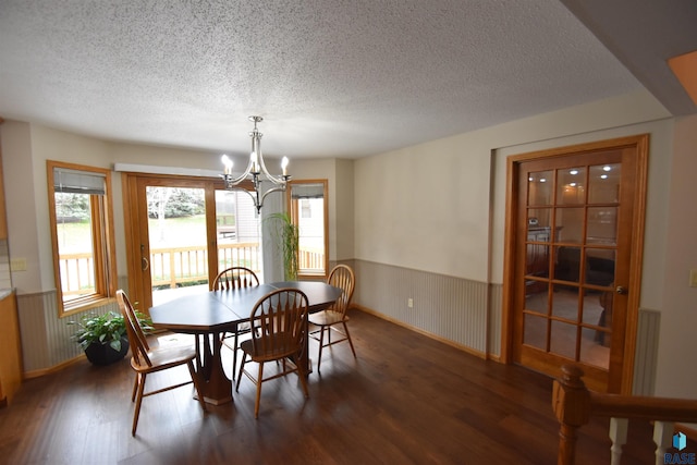 dining room featuring dark hardwood / wood-style flooring, a textured ceiling, and a notable chandelier