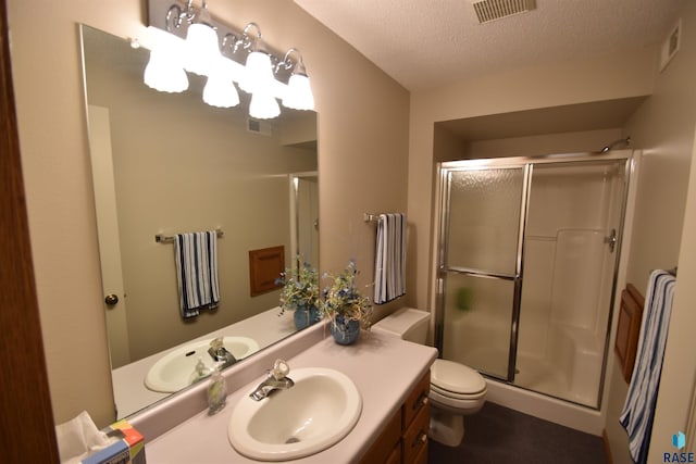 bathroom featuring a shower with door, vanity, a textured ceiling, and toilet