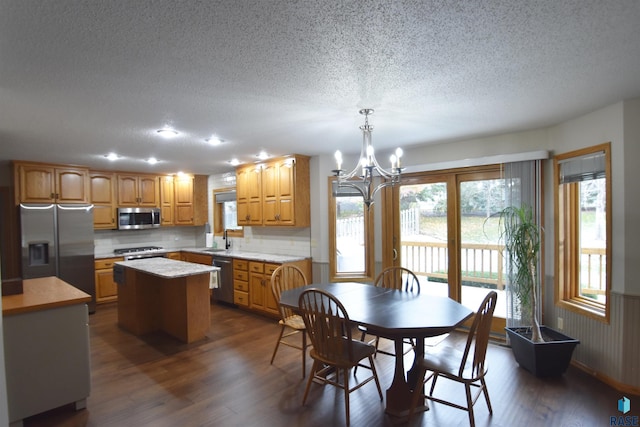 dining area with a notable chandelier, dark hardwood / wood-style floors, sink, and a textured ceiling