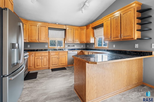 kitchen with kitchen peninsula, sink, appliances with stainless steel finishes, and vaulted ceiling