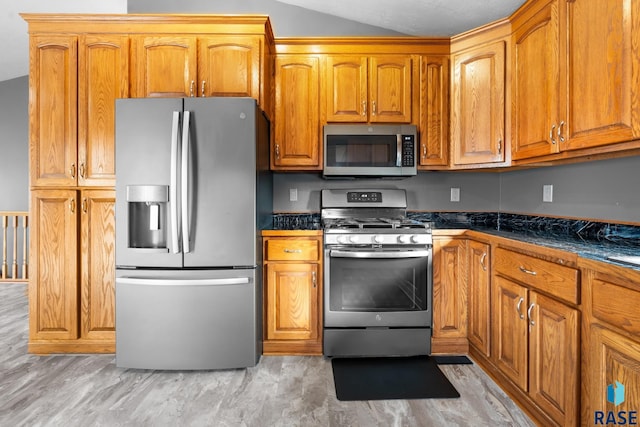 kitchen with light hardwood / wood-style floors, dark stone countertops, stainless steel appliances, and vaulted ceiling