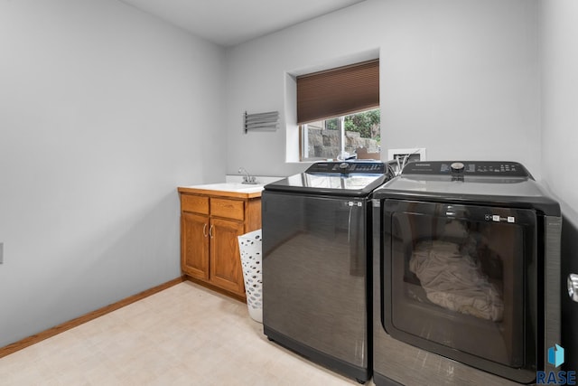 washroom with cabinets, sink, and washing machine and clothes dryer