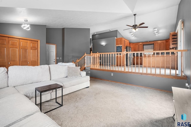 carpeted living room with ceiling fan and vaulted ceiling