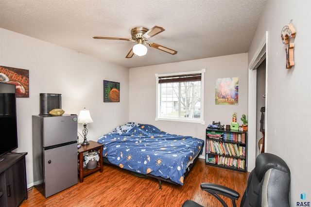 bedroom with ceiling fan, hardwood / wood-style floors, and a textured ceiling