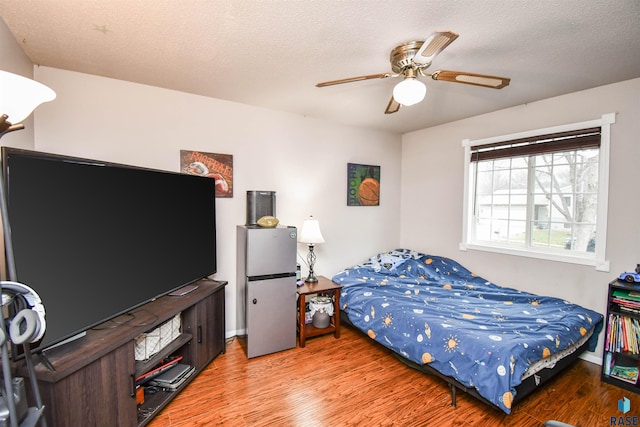 bedroom featuring hardwood / wood-style floors, ceiling fan, and a textured ceiling