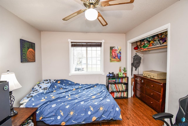 bedroom with ceiling fan, dark hardwood / wood-style flooring, a textured ceiling, and a closet