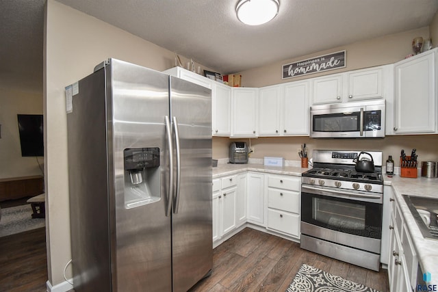 kitchen with dark hardwood / wood-style flooring, white cabinetry, a textured ceiling, and appliances with stainless steel finishes