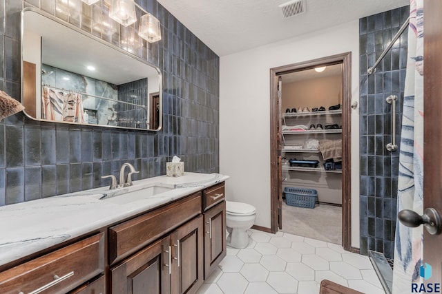 bathroom with vanity, tile patterned floors, a shower with curtain, toilet, and tile walls