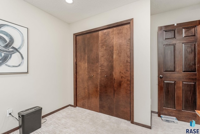 bedroom with light colored carpet, a textured ceiling, and a closet