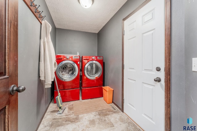 clothes washing area with separate washer and dryer and a textured ceiling