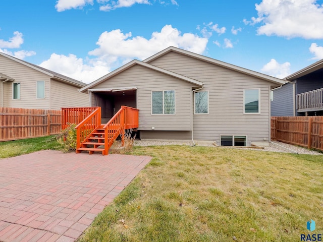 back of property with a deck, a yard, and a patio