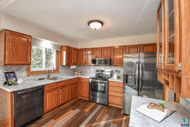 kitchen featuring backsplash, a textured ceiling, stainless steel appliances, dark wood-type flooring, and sink