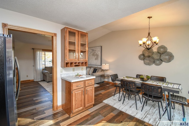 kitchen with a notable chandelier, dark hardwood / wood-style floors, stainless steel refrigerator, hanging light fixtures, and lofted ceiling