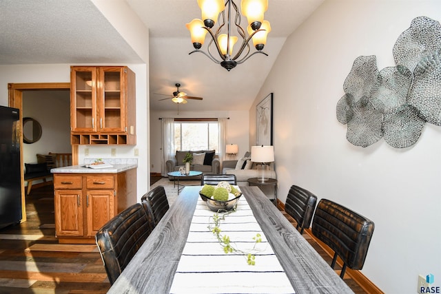 dining space featuring ceiling fan with notable chandelier, dark hardwood / wood-style floors, and vaulted ceiling