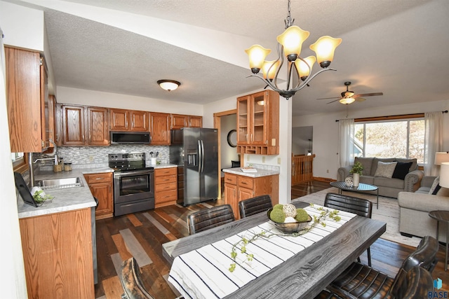 kitchen featuring ceiling fan with notable chandelier, stainless steel appliances, sink, pendant lighting, and dark hardwood / wood-style floors