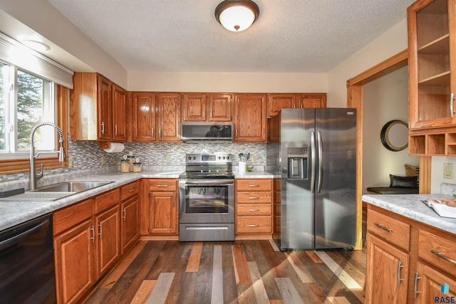 kitchen with sink, dark hardwood / wood-style flooring, backsplash, a textured ceiling, and appliances with stainless steel finishes