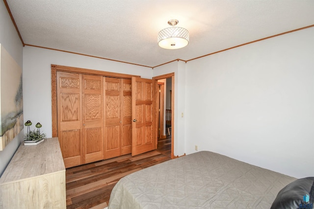 bedroom with crown molding, a closet, dark wood-type flooring, and a textured ceiling