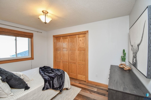 bedroom with a closet, wood-type flooring, and a textured ceiling