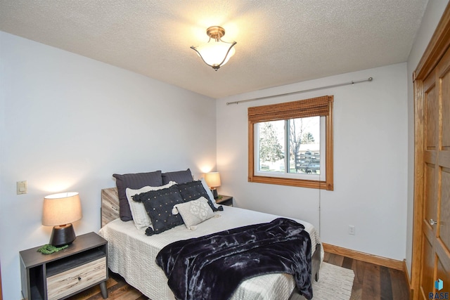 bedroom with a textured ceiling and dark hardwood / wood-style flooring