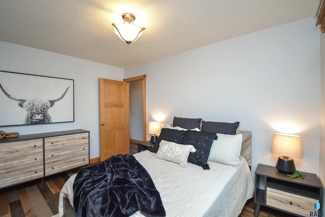 bedroom with a textured ceiling and dark hardwood / wood-style floors