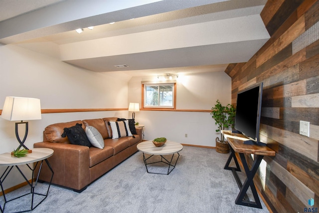 carpeted living room with wood walls