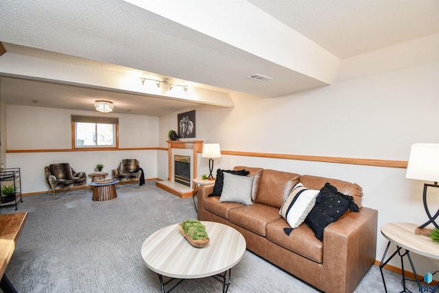 carpeted living room featuring a textured ceiling and a tile fireplace