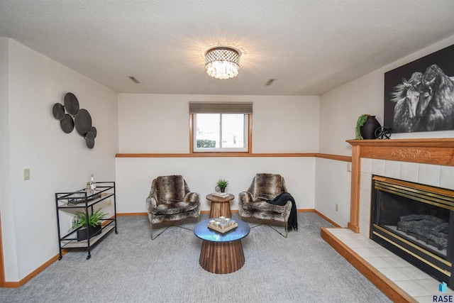 living area featuring a tile fireplace, light carpet, and a textured ceiling