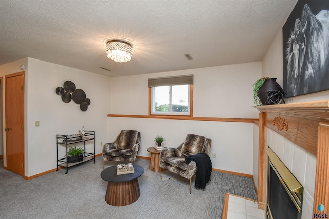 sitting room featuring a tile fireplace, a textured ceiling, and carpet floors