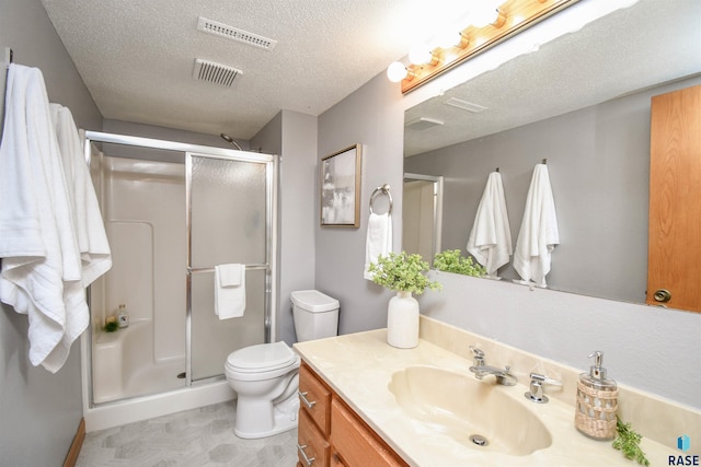 bathroom featuring vanity, a textured ceiling, toilet, and a shower with door