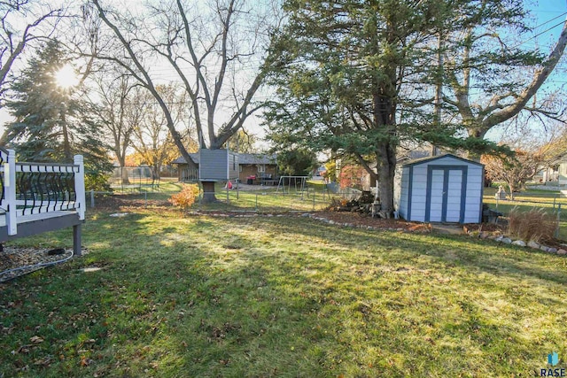 view of yard featuring a wooden deck, a trampoline, and a storage shed