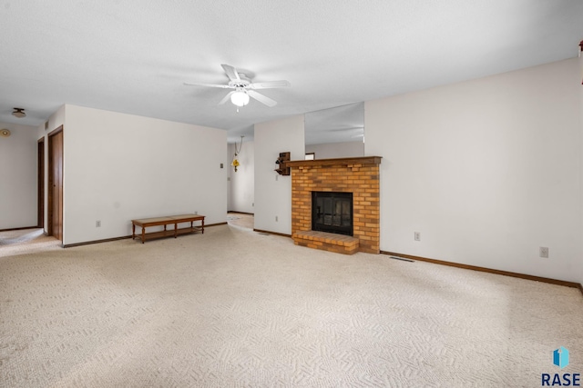 unfurnished living room with a fireplace, carpet flooring, and ceiling fan