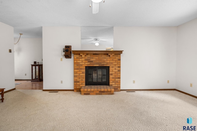 unfurnished living room featuring carpet, ceiling fan, a fireplace, and a textured ceiling