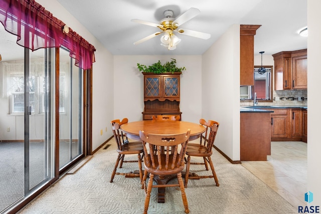 tiled dining room with ceiling fan and sink