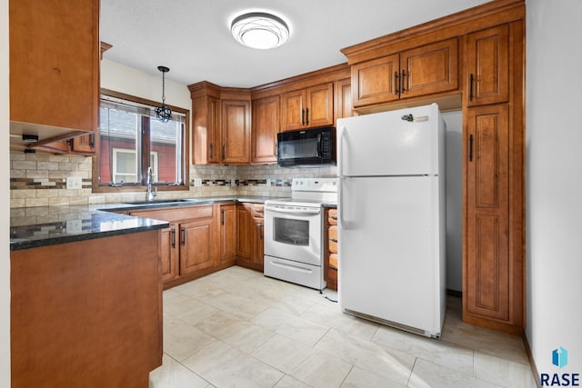 kitchen with white appliances, dark stone counters, hanging light fixtures, sink, and tasteful backsplash