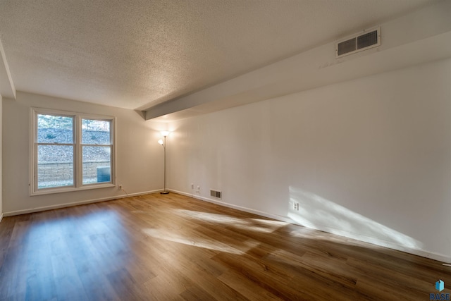 empty room with hardwood / wood-style floors and a textured ceiling