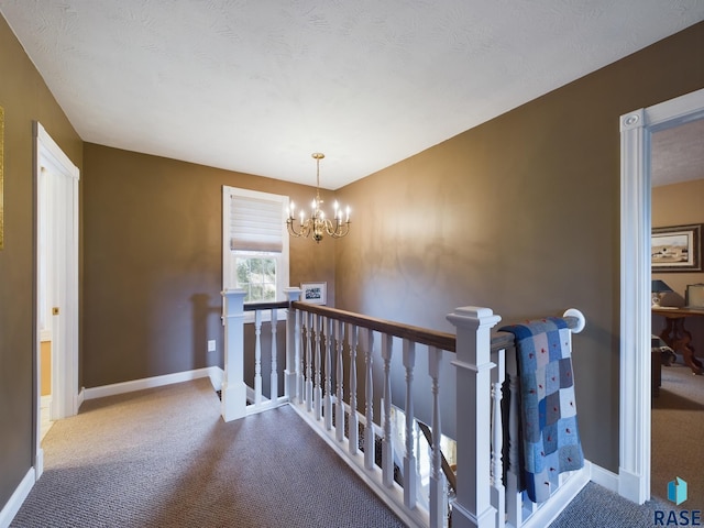 hallway featuring carpet floors, a textured ceiling, and a chandelier