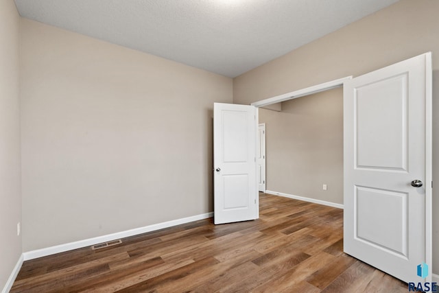 unfurnished bedroom with wood-type flooring and a textured ceiling