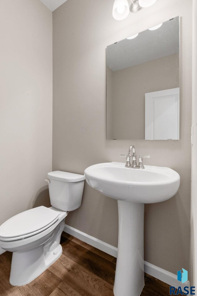 bathroom with hardwood / wood-style floors, toilet, and sink