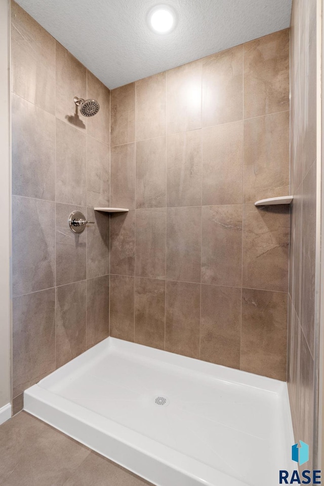 bathroom featuring a tile shower and a textured ceiling