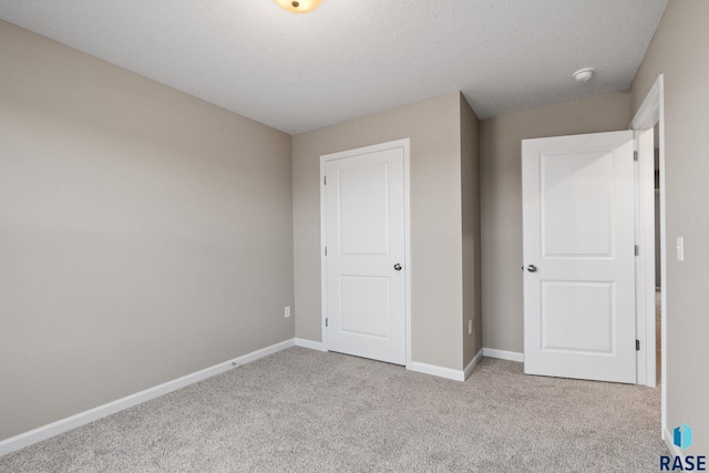 unfurnished bedroom featuring a textured ceiling and light carpet